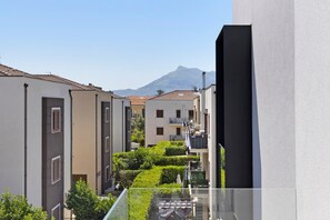 Um edifício residencial com varandas, céu claro e uma montanha ao fundo.