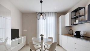 Een moderne keuken met een eethoek, een televisie en een hanglamp.