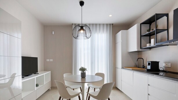 A modern kitchen with a dining area, a TV, and a pendant light. - Etesia Apartment with Balcony, Wi-Fi and Air Conditioning (Santa Flavia)