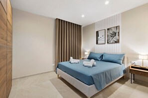A bedroom with a bed, bedside tables, a lamp, and a window with curtains.