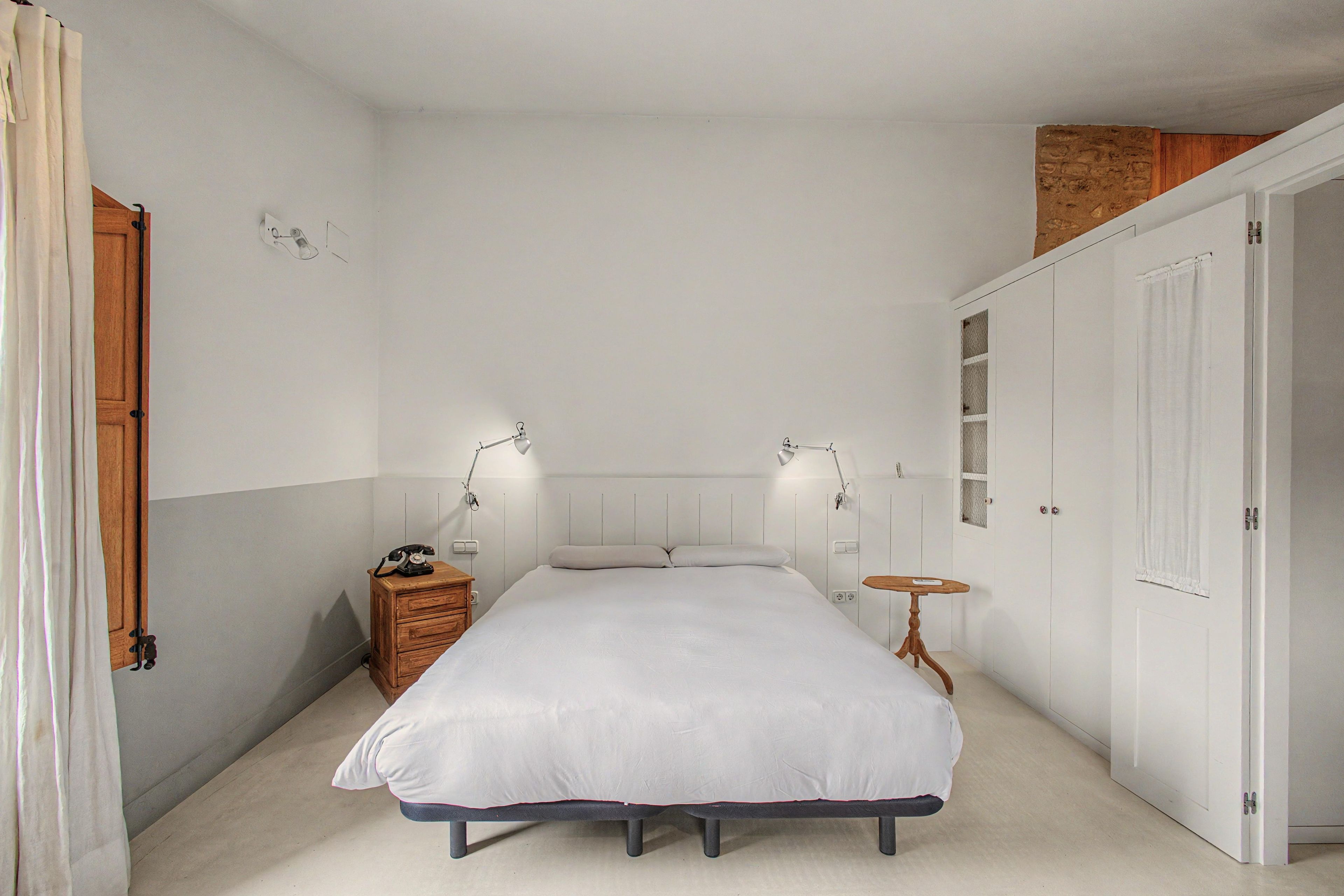 Une chambre à coucher avec un lit, des lampes de chevet, une table de chevet en bois et une petite table.