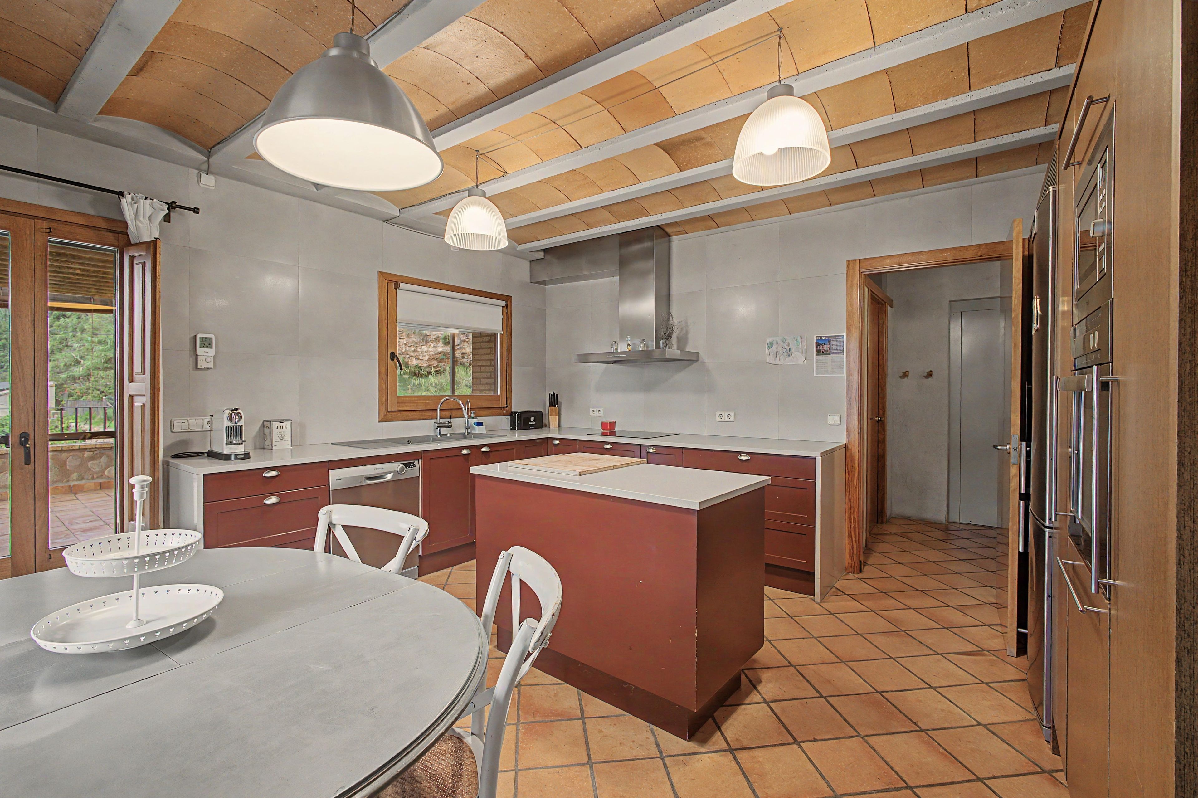 Una cucina moderna con isola centrale, illuminazione a sospensione e zona pranzo con tavolo e sedie rotonde.