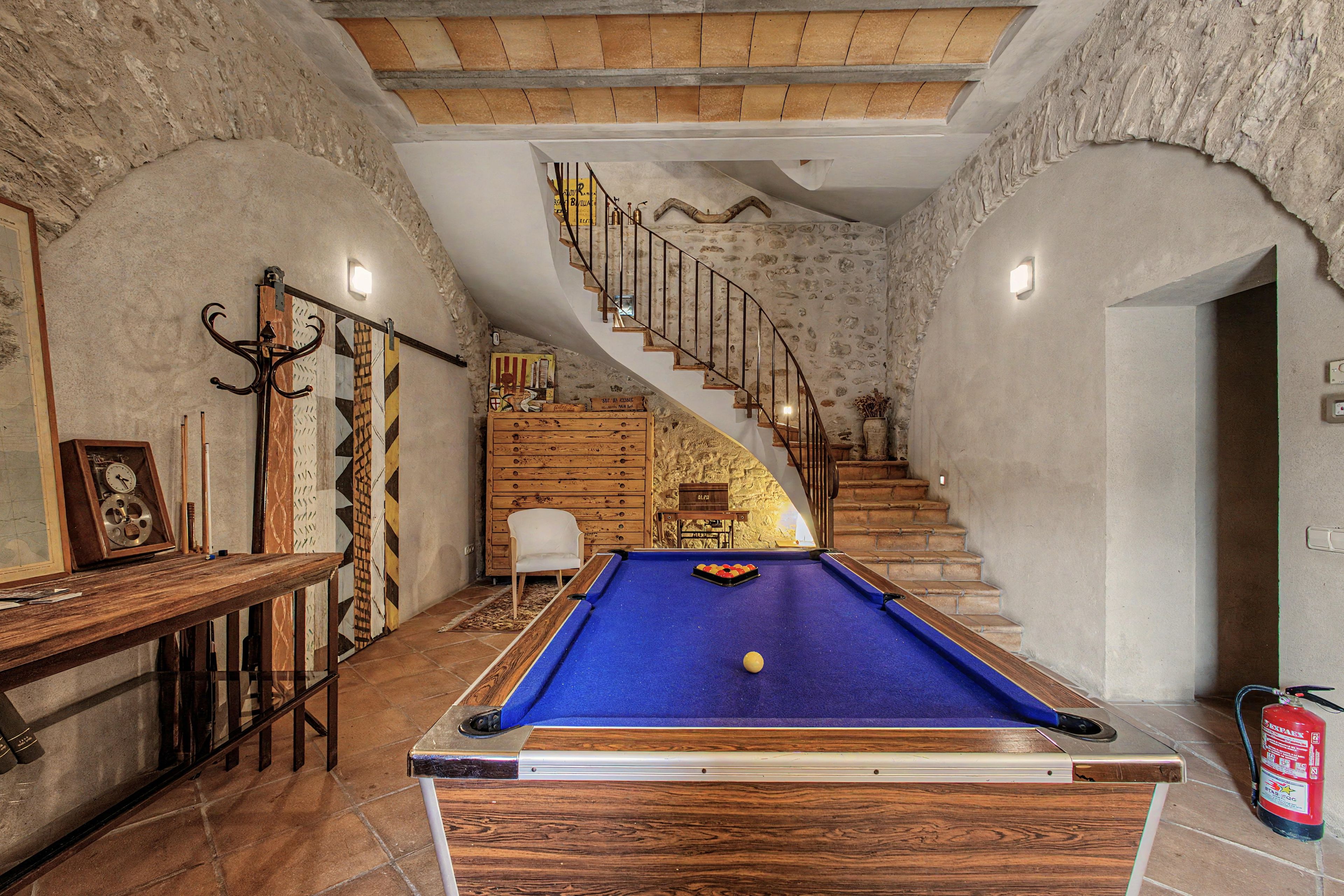 A pool table with a blue felt surface, a white cue ball, and a billiard rack with balls.