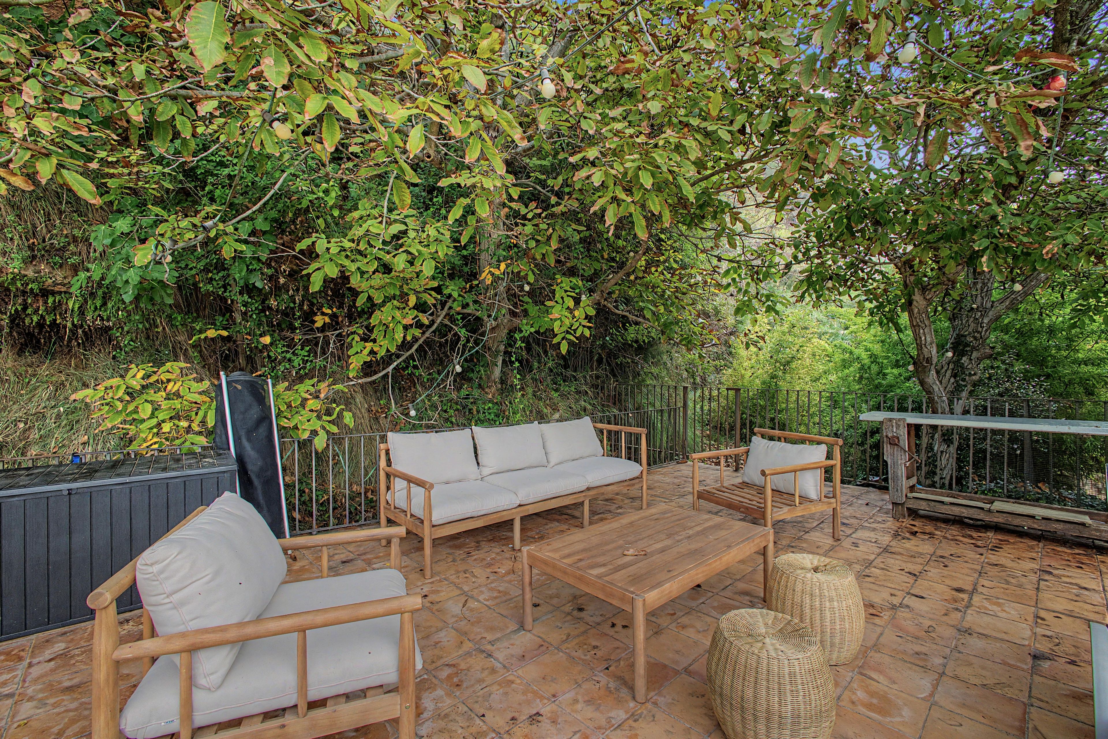 Eine Terrasse im Freien mit Holzmöbeln, darunter Sofas und ein Tisch.