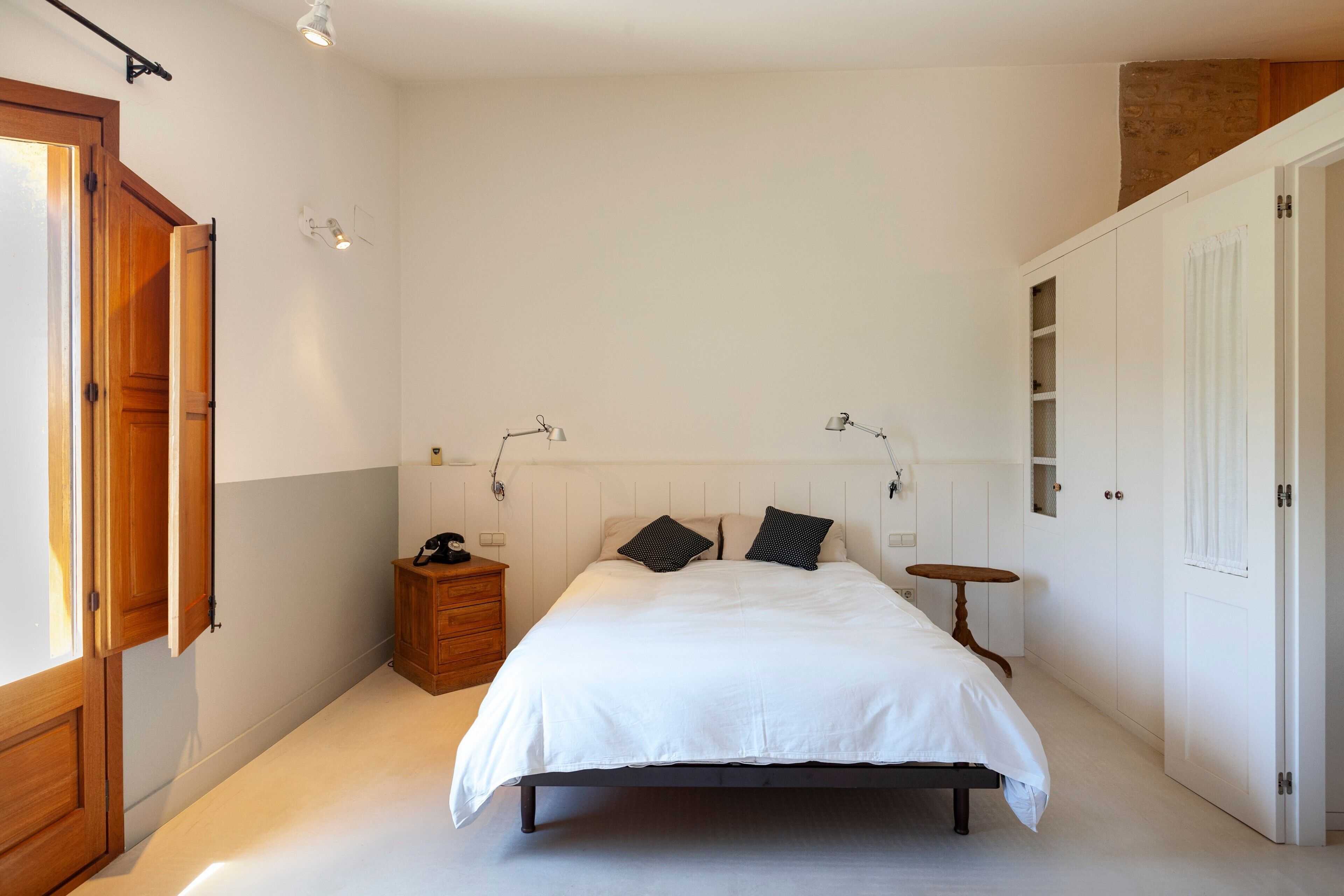 Una camera da letto con un letto, lampade da comodino, un comodino, un armadio e una finestra.