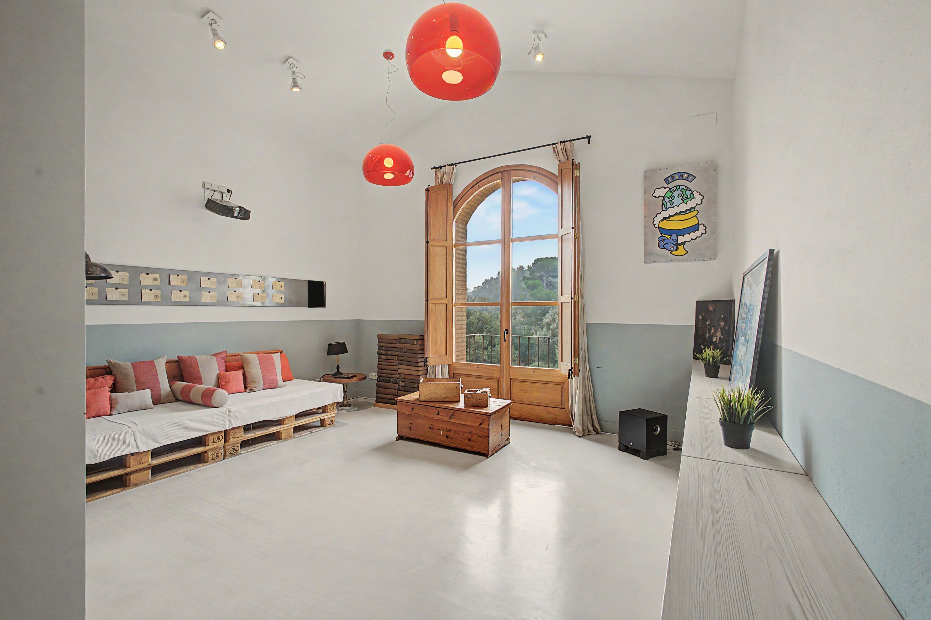 Una habitación con una cama, un cofre de madera, una ventana y un estante de pared con papeles.