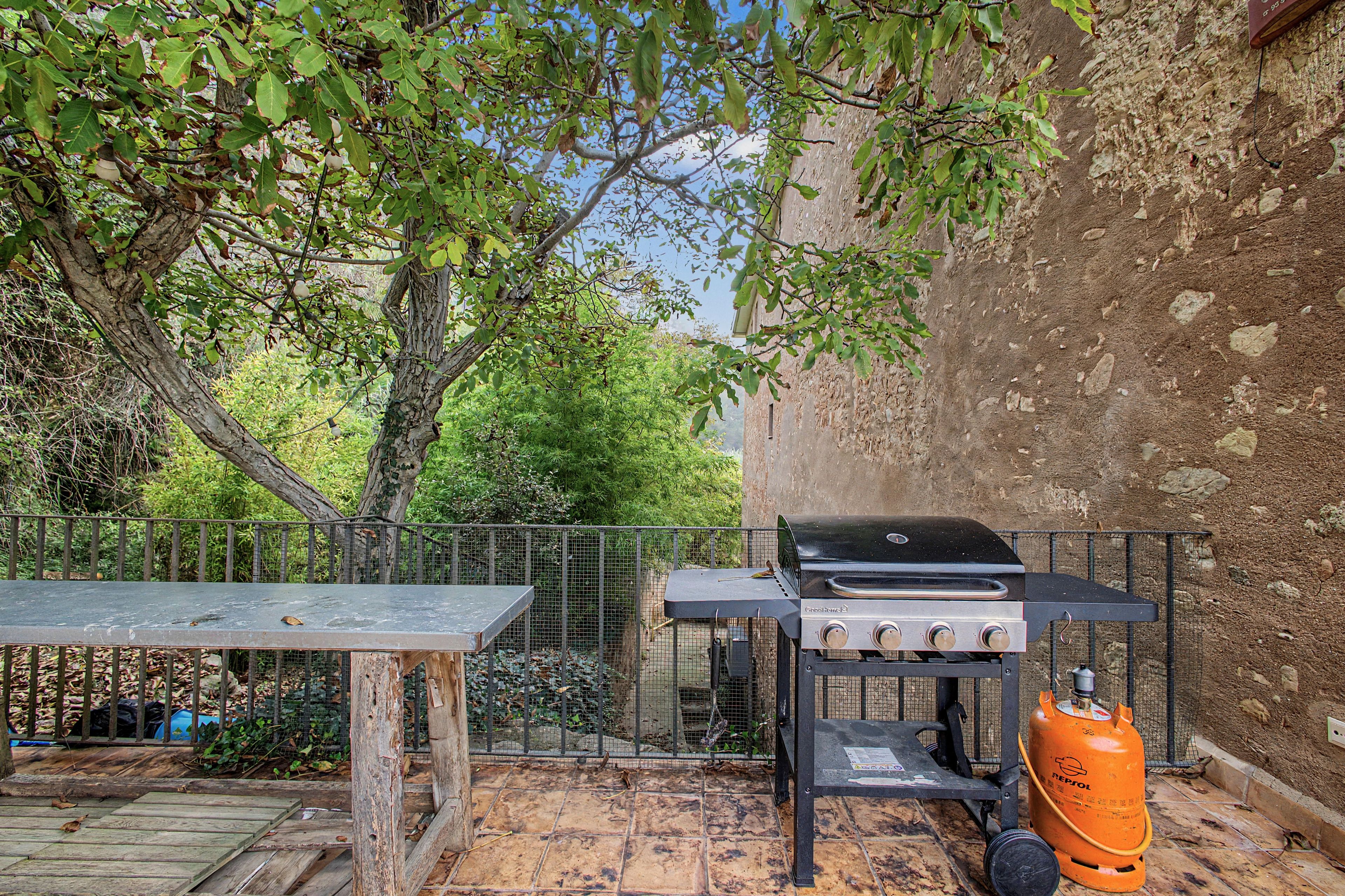 Un patio exterior con una parrilla, una mesa y una valla.