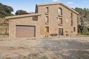 Um edifício de dois andares com garagem, várias janelas e um pequeno alpendre.