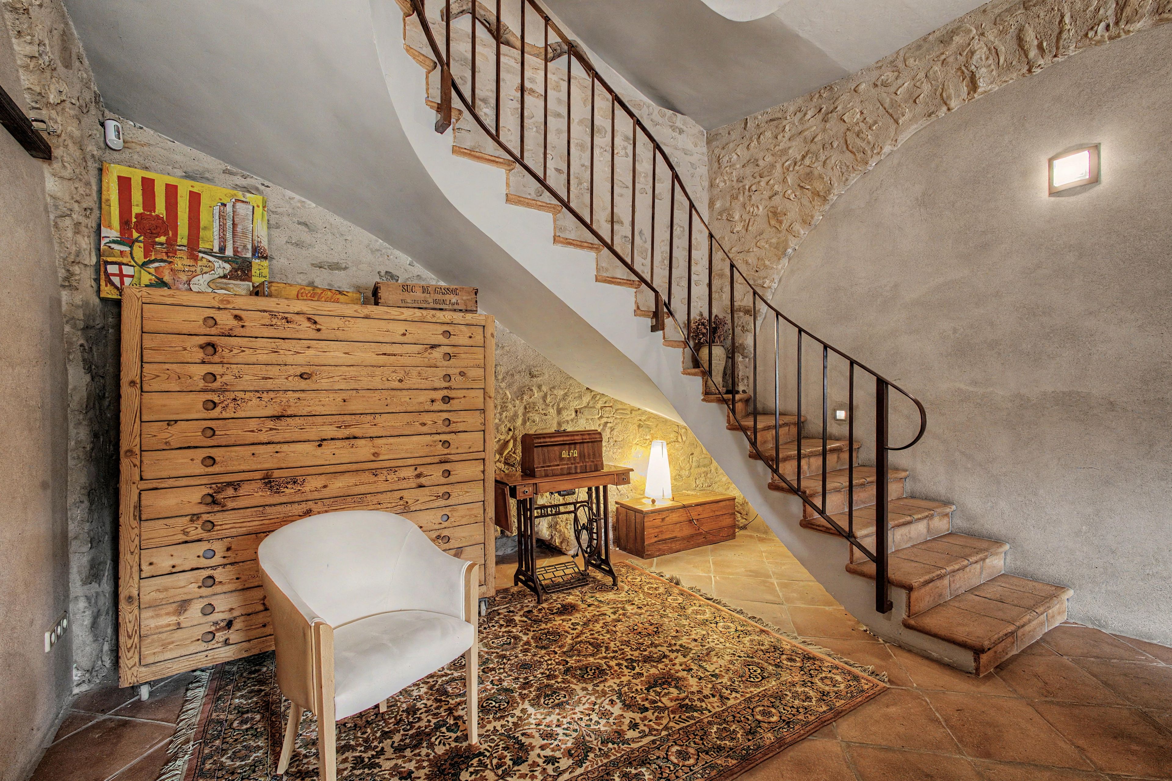 Una scala con ringhiera in legno e pareti in pietra, che conduce a un livello superiore.