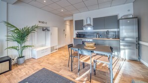 Una cucina moderna con elettrodomestici in acciaio inossidabile, una zona pranzo con tavolo e sedie, e una pianta in vaso.