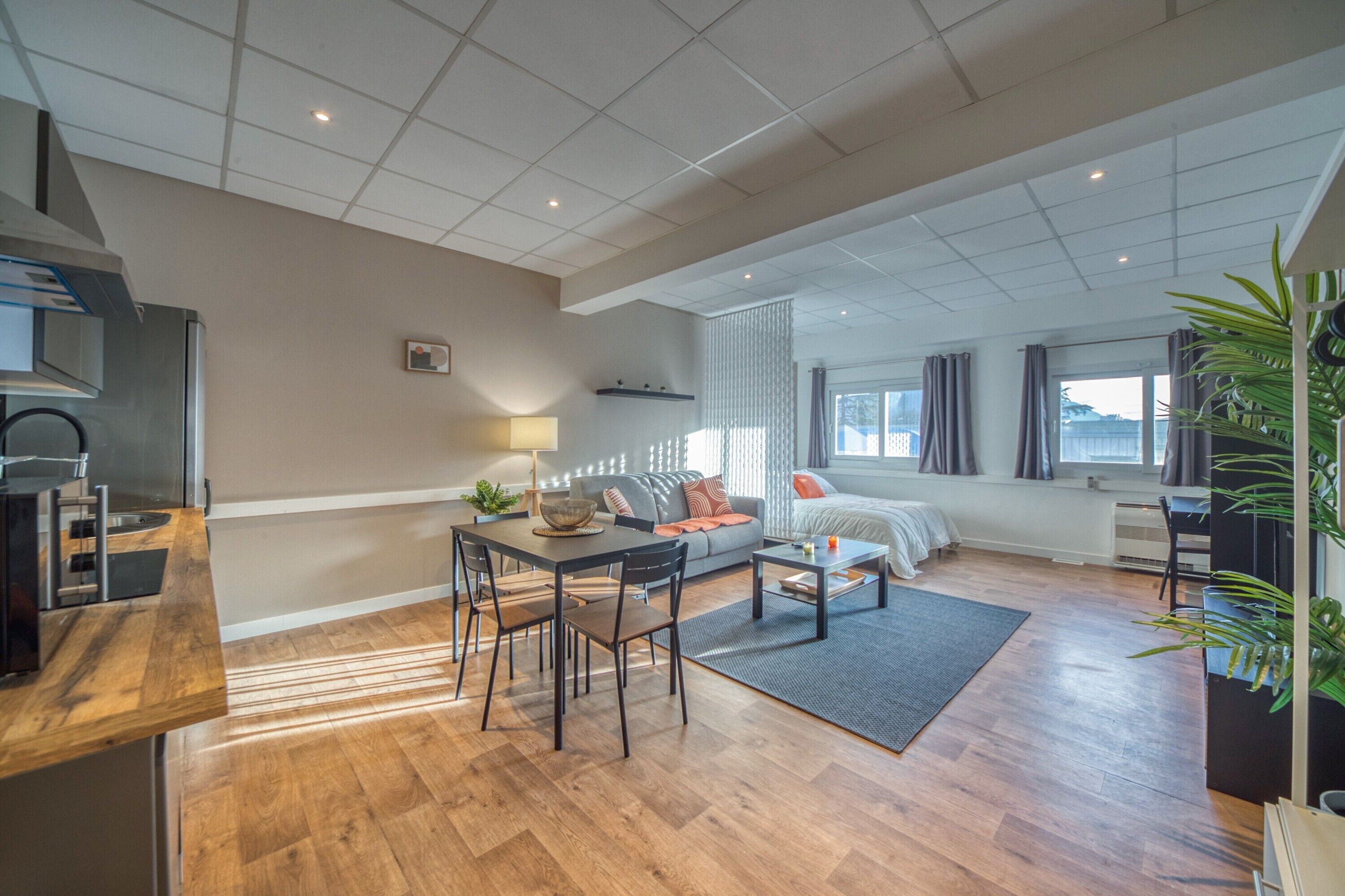 A modern living space with a dining area, sofa, and a bed.