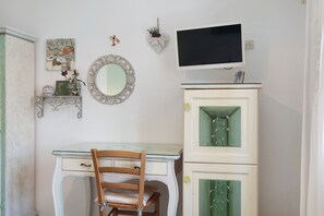 A room with a desk, chair, mirror, and a television on a cabinet. - "Casetta Azzurromare" Room 'Primavera' with Sea View, Wi-Fi and Air Conditioning (San Vito Lo Capo)