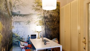 Une pièce dotée d’un parquet en bois à motifs chevrons, d’une table blanche avec des chaises, d’une lampe suspendue et d’une fresque murale.