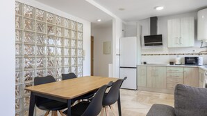 Eine moderne Küche mit Holztisch und -stühlen, einer Mikrowelle und einem Kühlschrank.