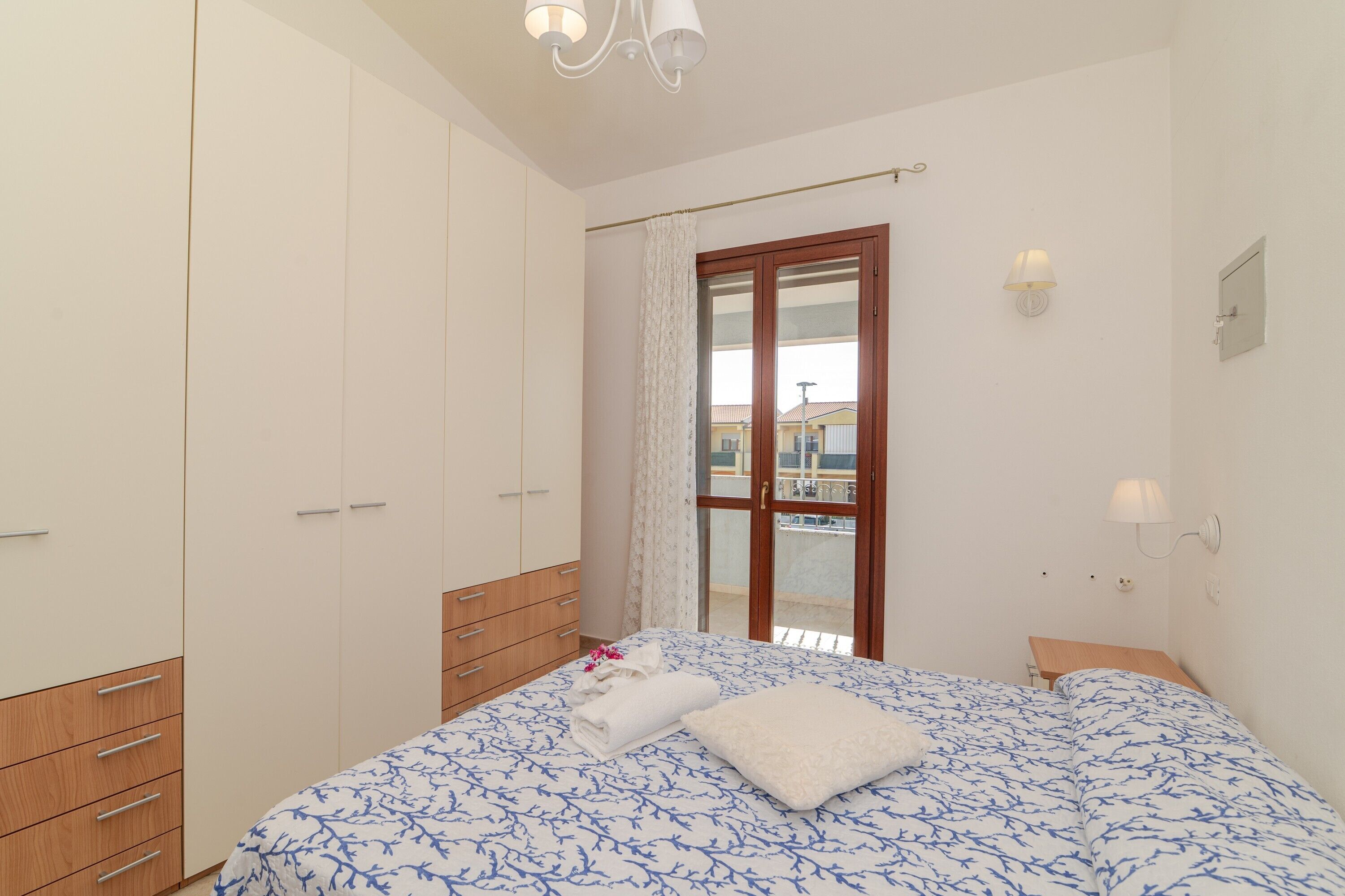 Une chambre à coucher avec un lit, une armoire, une fenêtre avec des rideaux et un balcon.