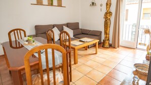 A living room with a sofa, dining table, chairs, a coffee table, and a decorative statue.