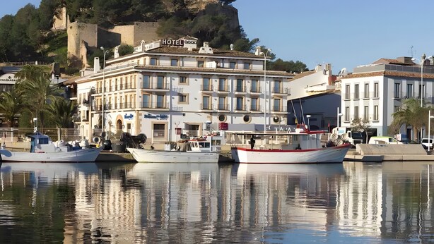 A hotel with a view of a hill and a body of water.