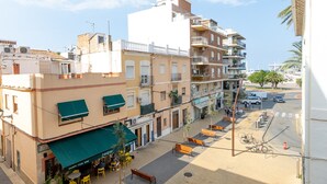 A street view with buildings, outdoor seating, and a clear sky.