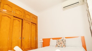 A hotel room with a bed, wooden wardrobe, and an air conditioning unit.