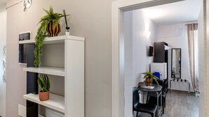A modern hotel room with a dining area, a potted plant, a mirror, and a TV. - Accessible Room in Guest House (Verona)