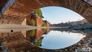 A bridge with a clear reflection in the water, a stone pathway, and a calm river. - Accessible Room in Guest House (Verona)