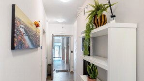 A hallway with a painting, a potted plant, and a shelf with a plant. - Accessible Room in Guest House (Verona)