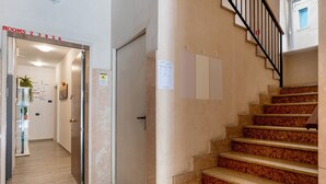 A hotel hallway with a staircase, numbered room signs, and a welcome sign. - Accessible Room in Guest House (Verona)