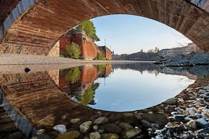 Un ponte con il suo riflesso nitido nell'acqua, un sentiero in pietra e un fiume tranquillo.