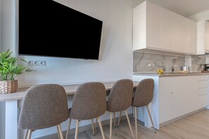 Una cucina moderna con una TV a schermo piatto, un'area pranzo con quattro sedie e una pianta in vaso.