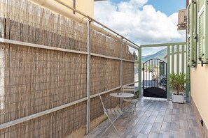 A courtyard with a bamboo fence, a metal gate, and a small round table with chairs. - 'Fenice' Room with Wi-Fi and Air Conditioning (Bastia)