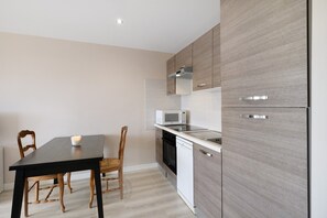 Eine moderne Küche mit Esstisch, Stühlen, Mikrowelle, Backofen und Geschirrspüler.