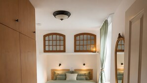 Una camera da letto con un letto, un armadio in legno, uno specchio e una finestra con tende.