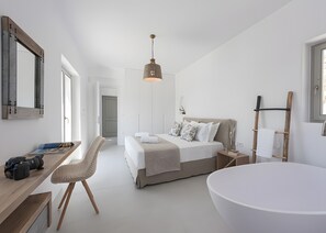 Ein modernes Schlafzimmer mit Bett, Schreibtisch, Stuhl, einer großen Badewanne und einer Pendelleuchte.