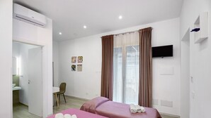 A hotel room with two beds, a TV, a desk, and a bathroom. - Le Stanze In Centro – Triple Room (Naples)