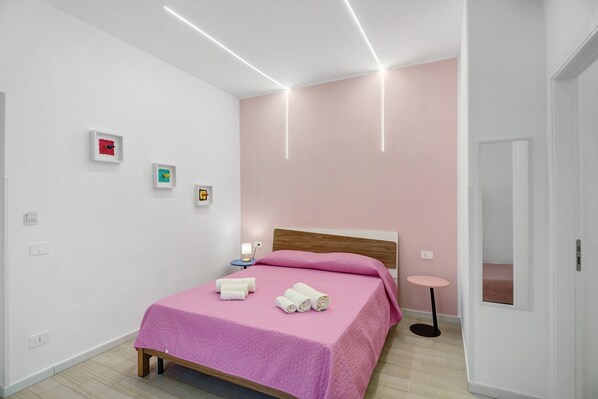 A modern bedroom with a bed, bedside tables, and wall art. - Le Stanze In Centro – Triple Room (Naples)