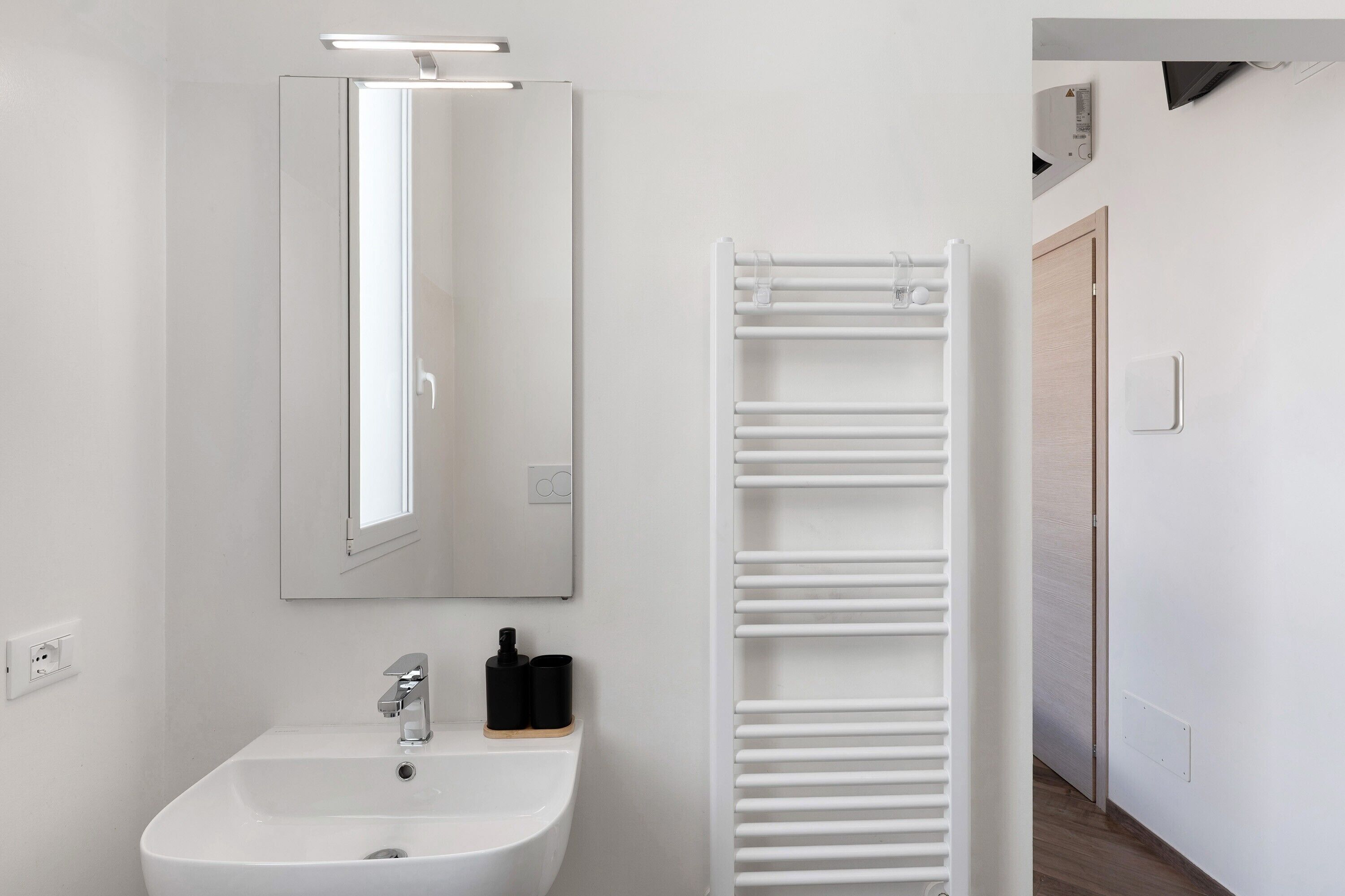 Une salle de bain moderne avec un lavabo blanc, un miroir et un porte-serviettes.