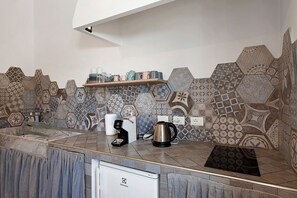 A kitchen with a modern design, featuring a coffee maker, kettle, and a shelf with cups. - 'Pegaso' Room with Wi-Fi and Air Conditioning (Bastia)