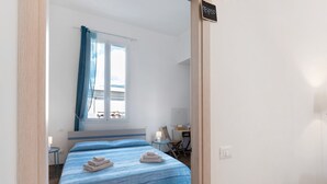 Ein Schlafzimmer mit einem Bett, einem Schreibtisch, einem Stuhl, einem Fenster mit Vorhängen und einem Schild an der Wand.