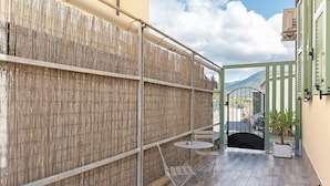 A courtyard with a bamboo fence, a metal gate, and a small round table with chairs. - Room 'Pesci' with Mountain View, Wi-Fi and Air Conditioning (Bastia)
