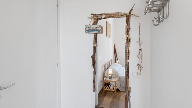A narrow hallway with a rustic wooden archway, a bed with a white headboard, and a wall-mounted light fixture. - Room 'Pesci' with Mountain View, Wi-Fi and Air Conditioning (Bastia)