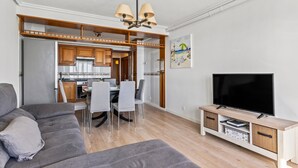Un salon moderne avec un canapé gris, un téléviseur à écran plat et un meuble TV en bois.