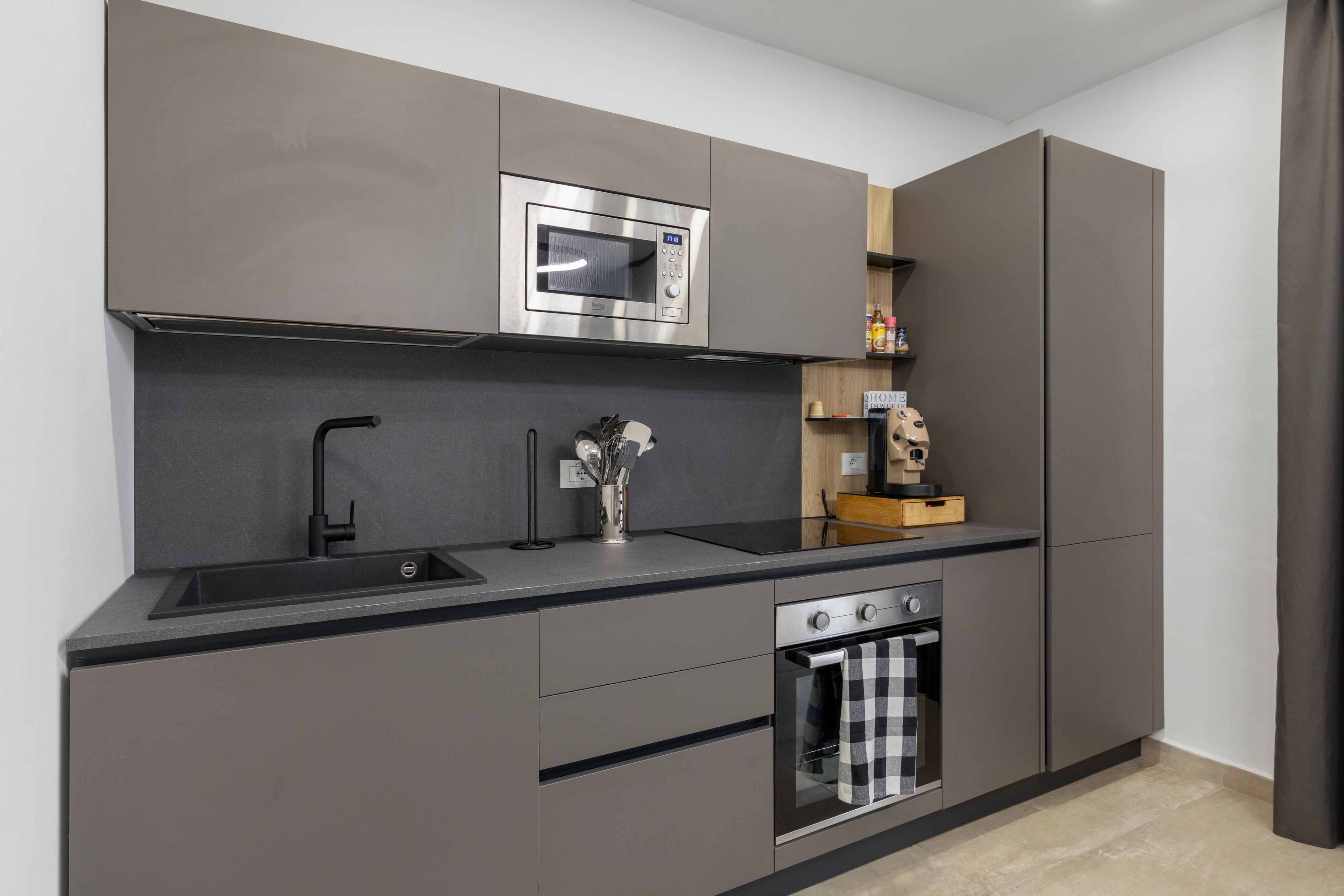 A modern kitchen with a built-in oven, a microwave, and a sink.