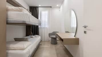 A compact hotel room with bunk beds, a desk, and a large mirror.