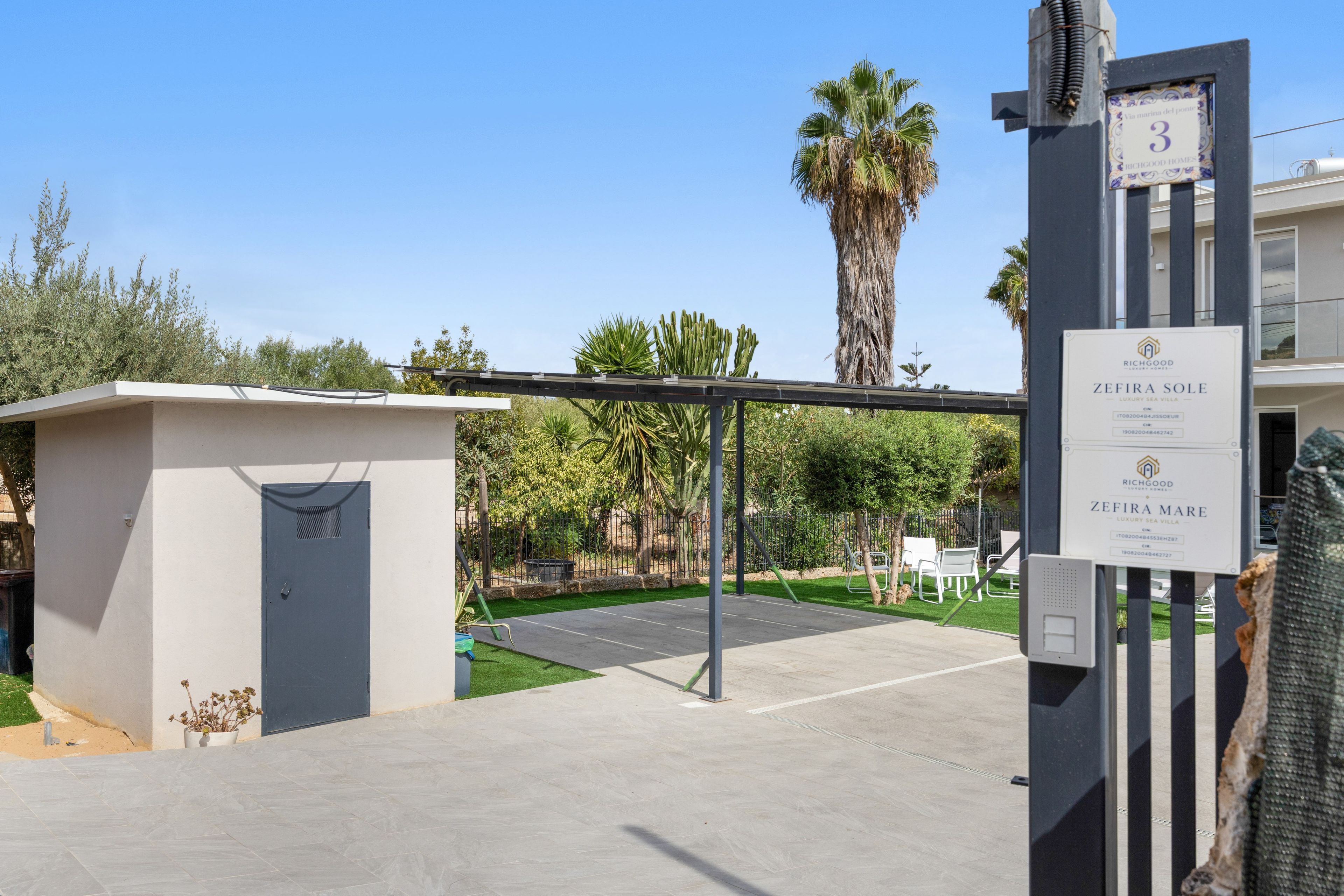 A gated entrance to a property with a sign indicating 'ZEFIRA MARE LUXURY SEA VILLA' and a number '3' on a post.