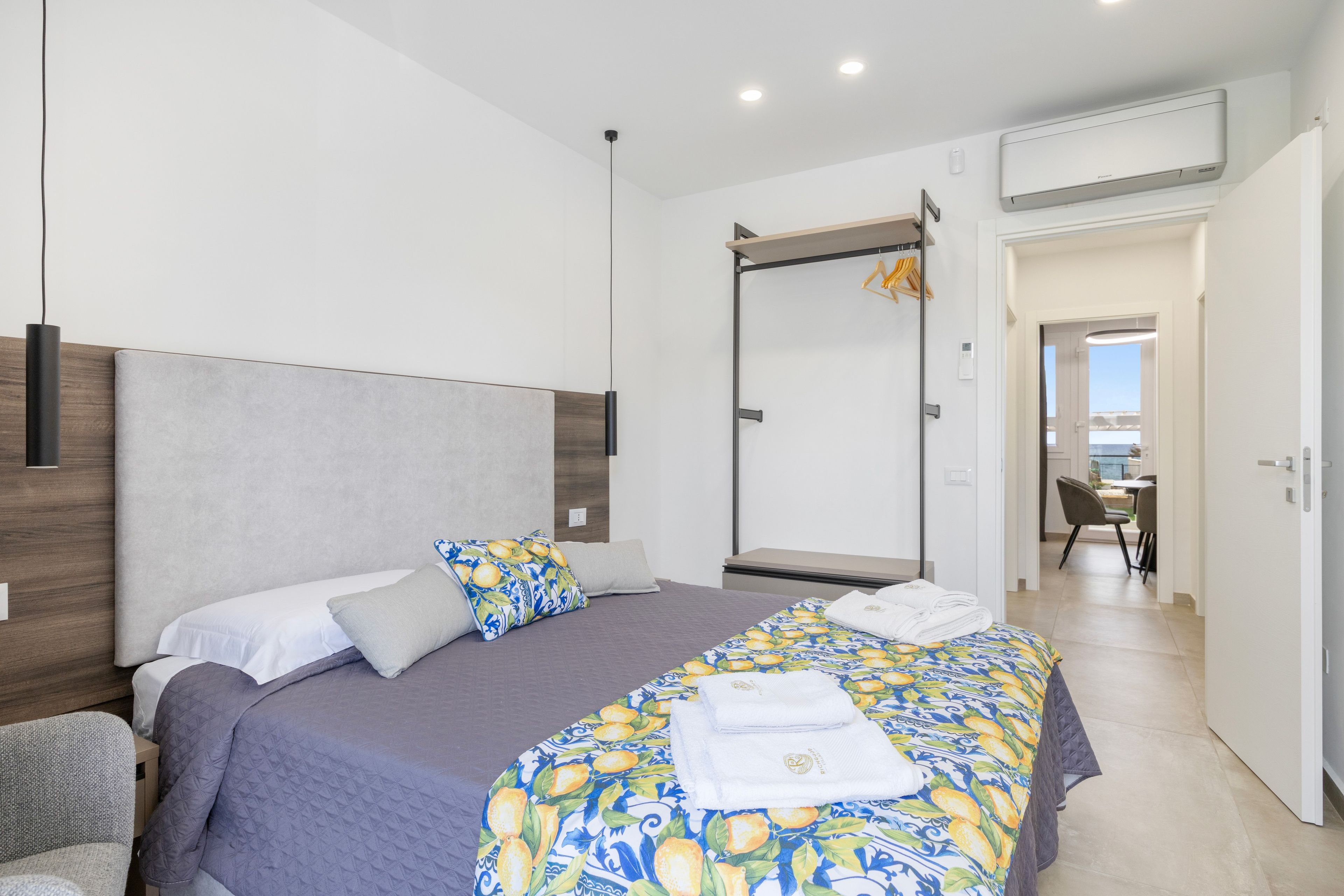 A modern hotel room with a large bed, a wardrobe, a mirror, and a view of the outside.