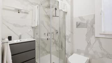Ein modernes Badezimmer mit einer Duschkabine, einer weißen Toilette und einem Waschtisch.