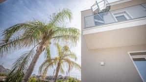 A modern building with a balcony, palm trees, and a clear sky. - Villa 'Zefira Mare' with Sea View, Wi-Fi, and Air Conditioning (Altavilla Milicia)