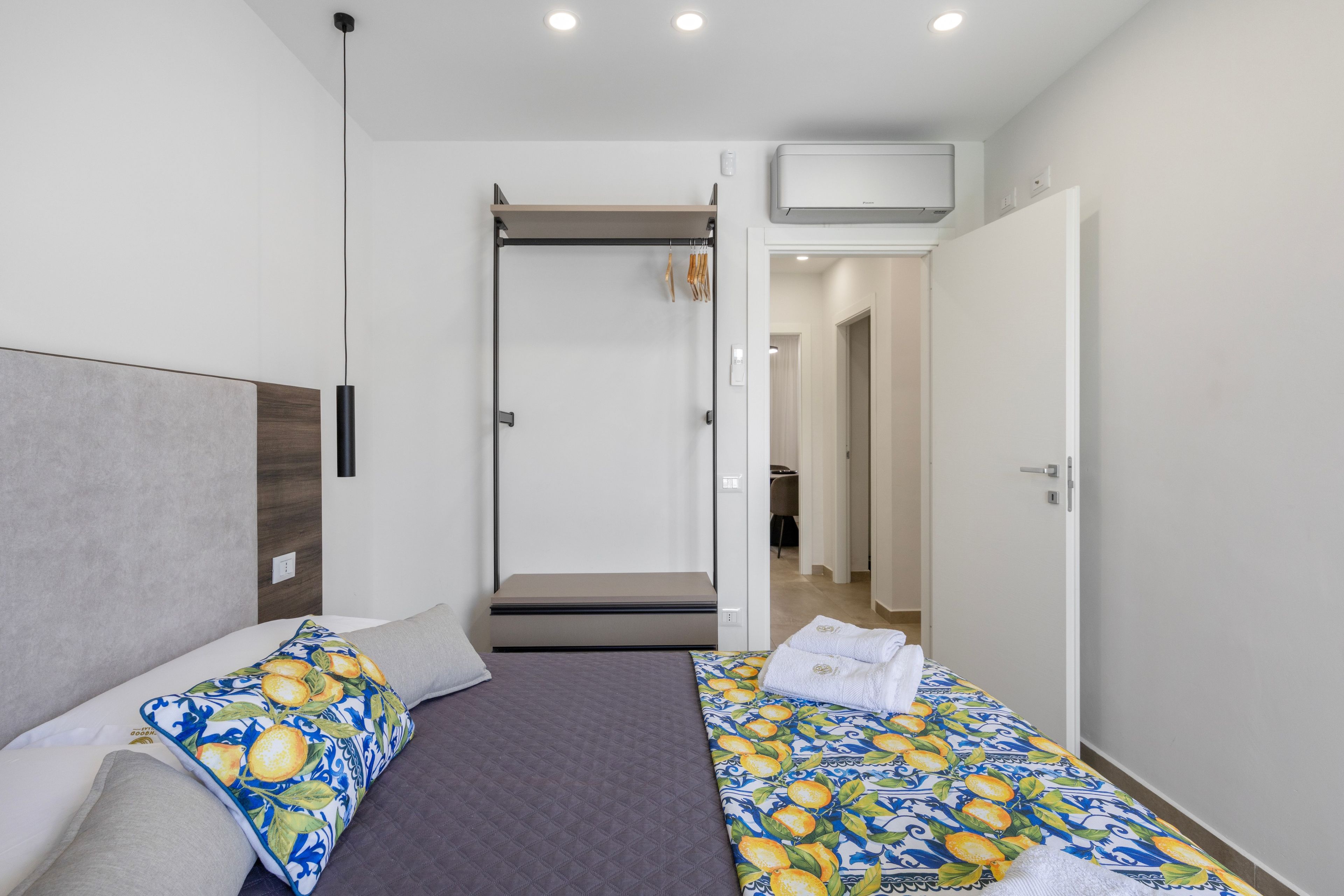 Una camera d'albergo con un letto, un armadio e un bagno visibile attraverso una porta aperta.