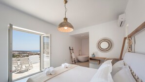 Een slaapkamer met een bed, een groot raam, een badkamer en uitzicht op de stad.