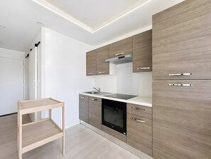 Une cuisine moderne avec des meubles en bois, un four encastré et une étagère en bois.
